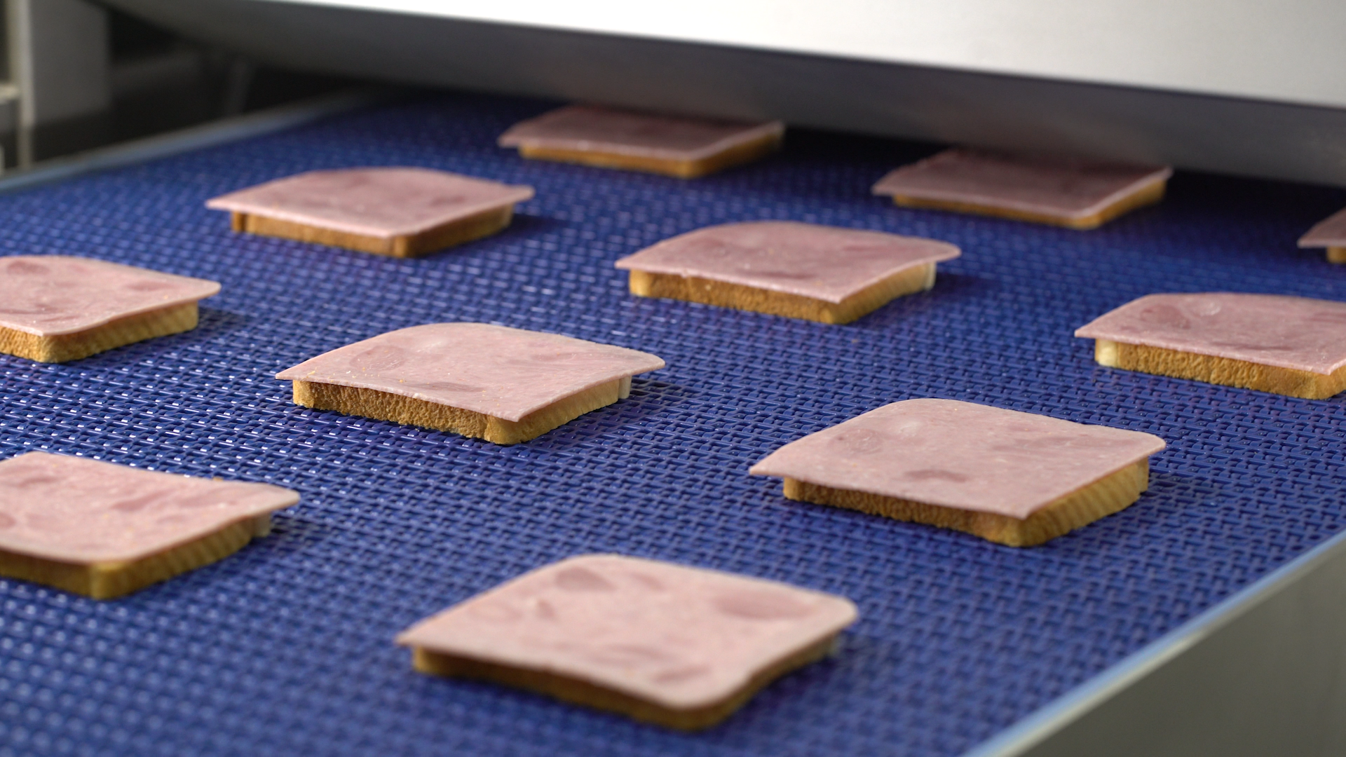 Bread and meat slices on a Grote Industrial Sandwich Slicer.