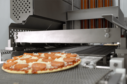 A pepperoni pizza going through a Grote pizza topping slicer machine.