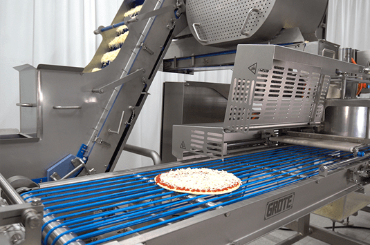 A pizza going through Grote's topping applicator equipment. 