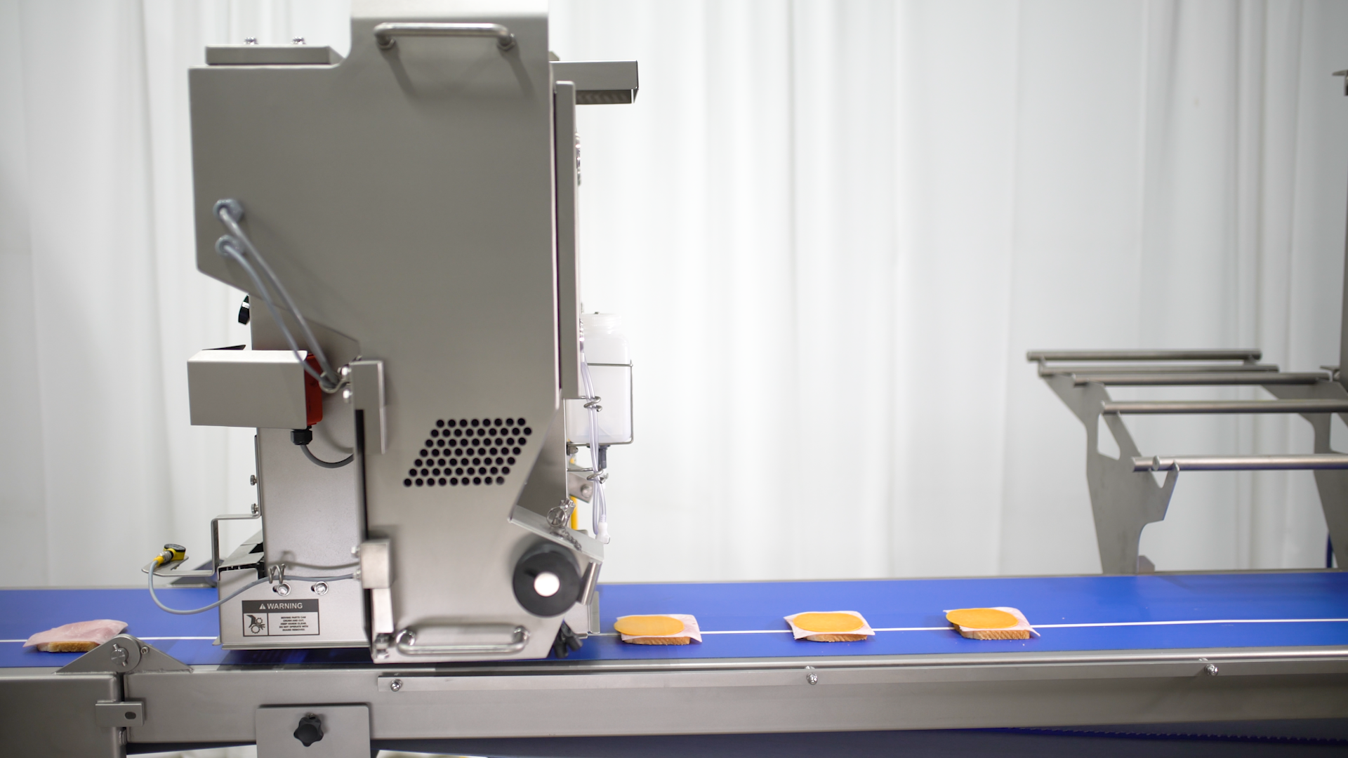 A pepperoni pizza going through a Grote pizza topping slicer machine.