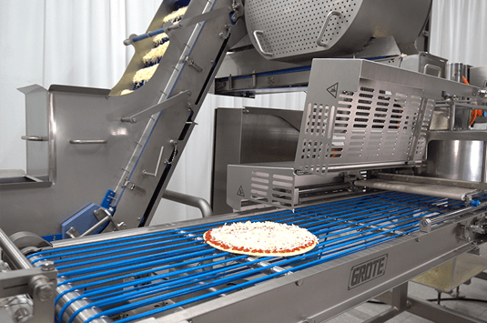A pizza going through Grote's topping applicator equipment.