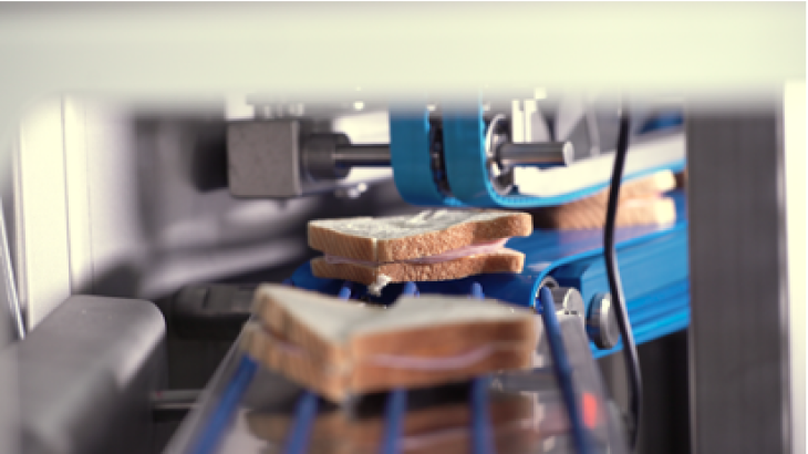 Sandwiches being cut in half by a sandwich cutter on a sandwich assembly line Sandwiches being cut in half by a sandwich cutter on a sandwich assembly line